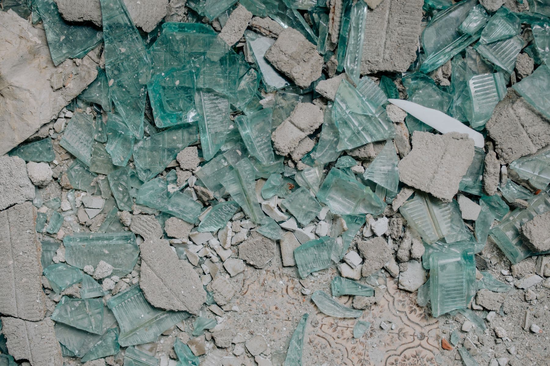 Broken chunks of concrete mixed with shards of green glass block.